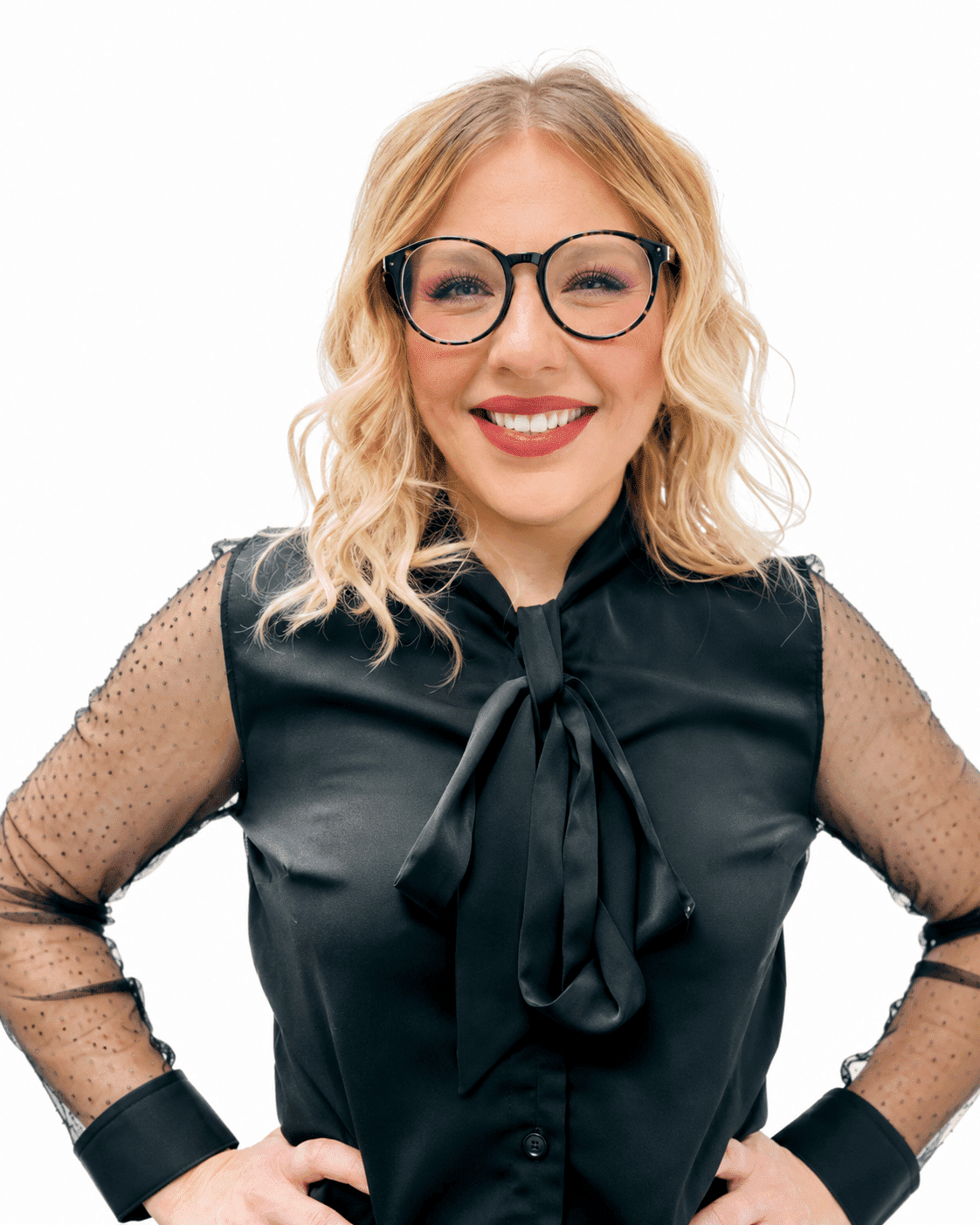 Smiling woman in black blouse with bow tie and glasses against white background.