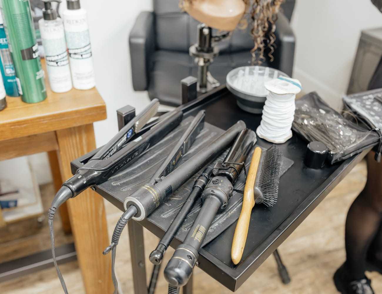Hair styling tools and products on a salon cart.
