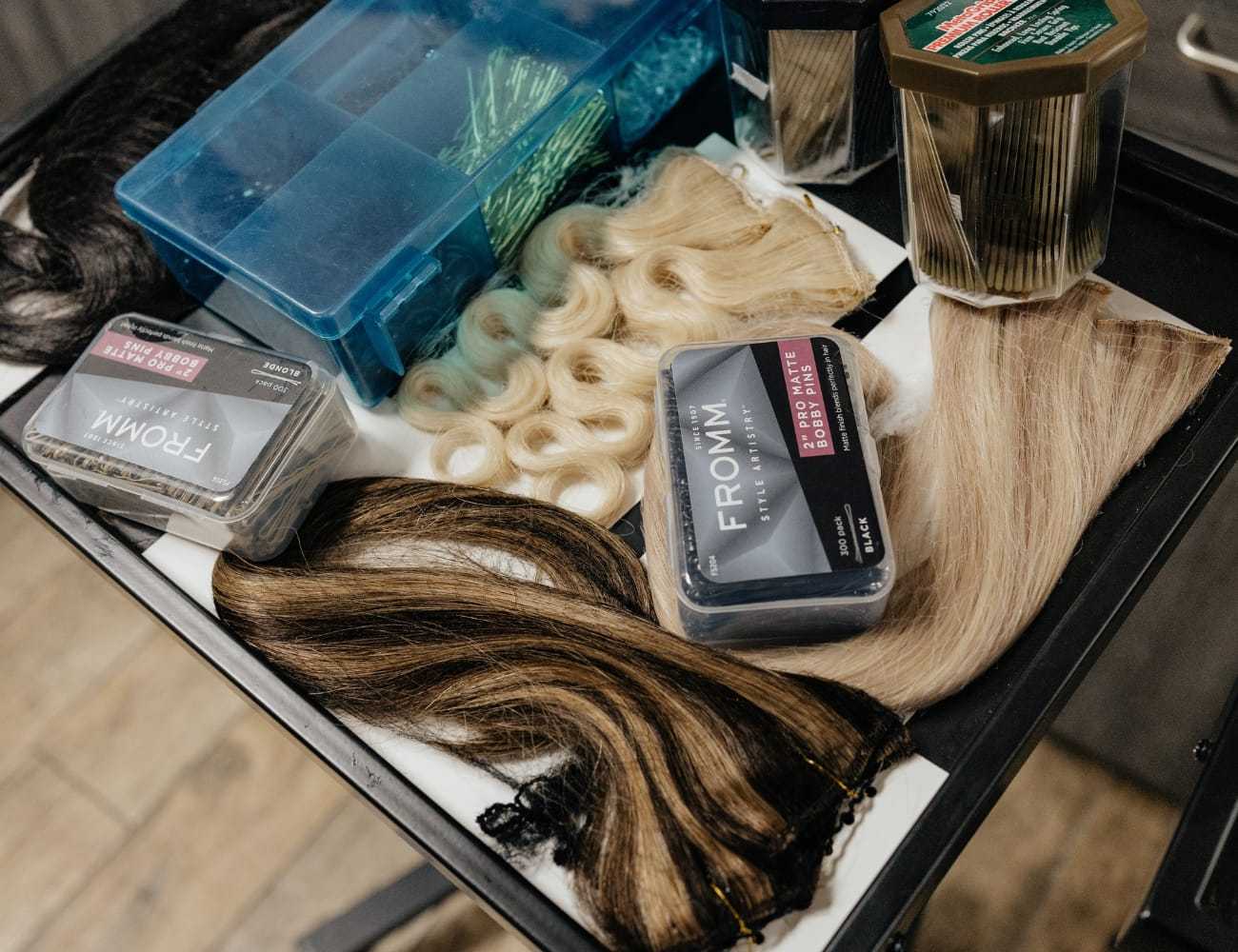 Various hair extensions and styling tools on a salon tray.